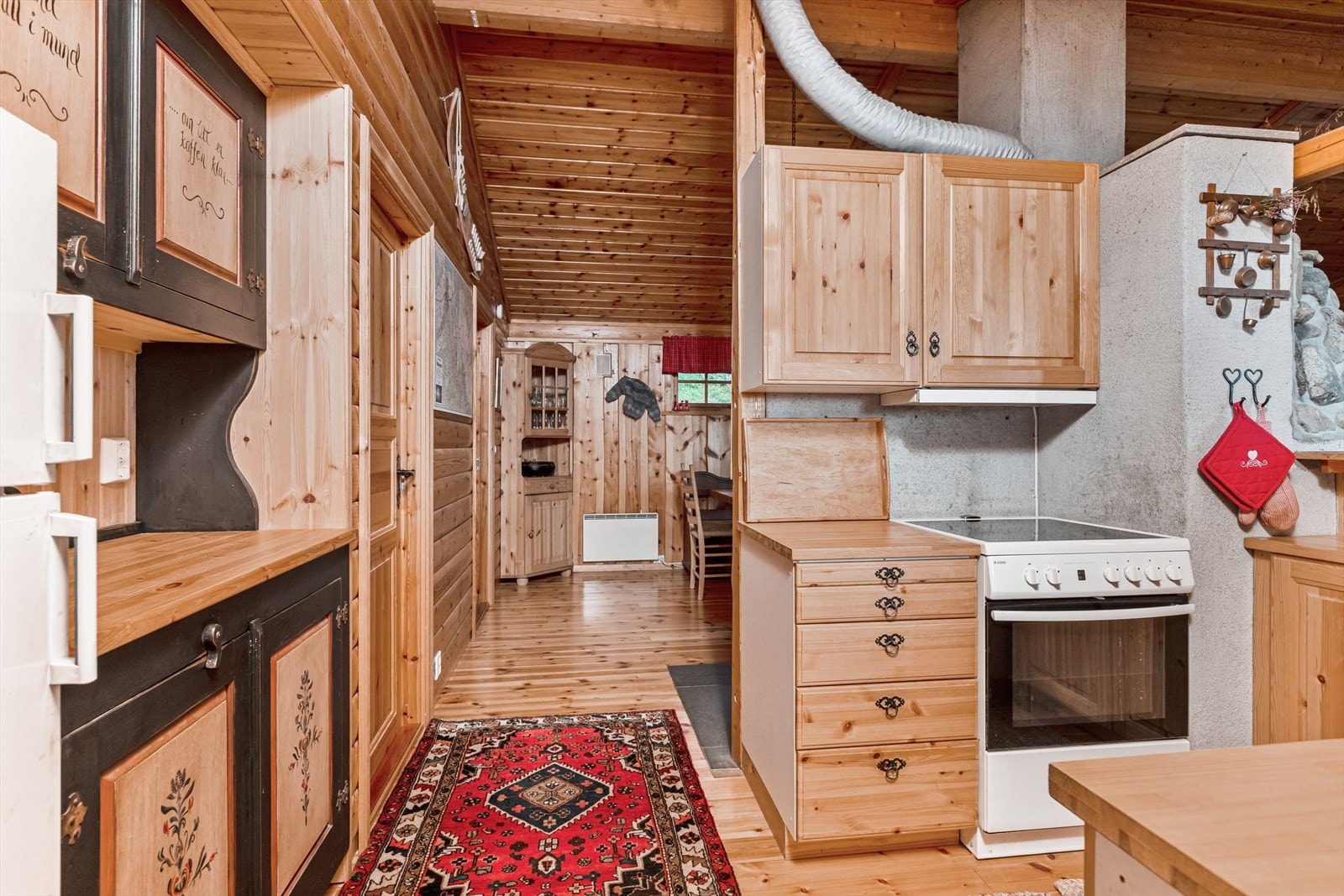Kjøkkenet har en sjarmerende innredning i hyttestil med profilerte fronter i furu, heltre benk og hvitevarer. Galleribilde