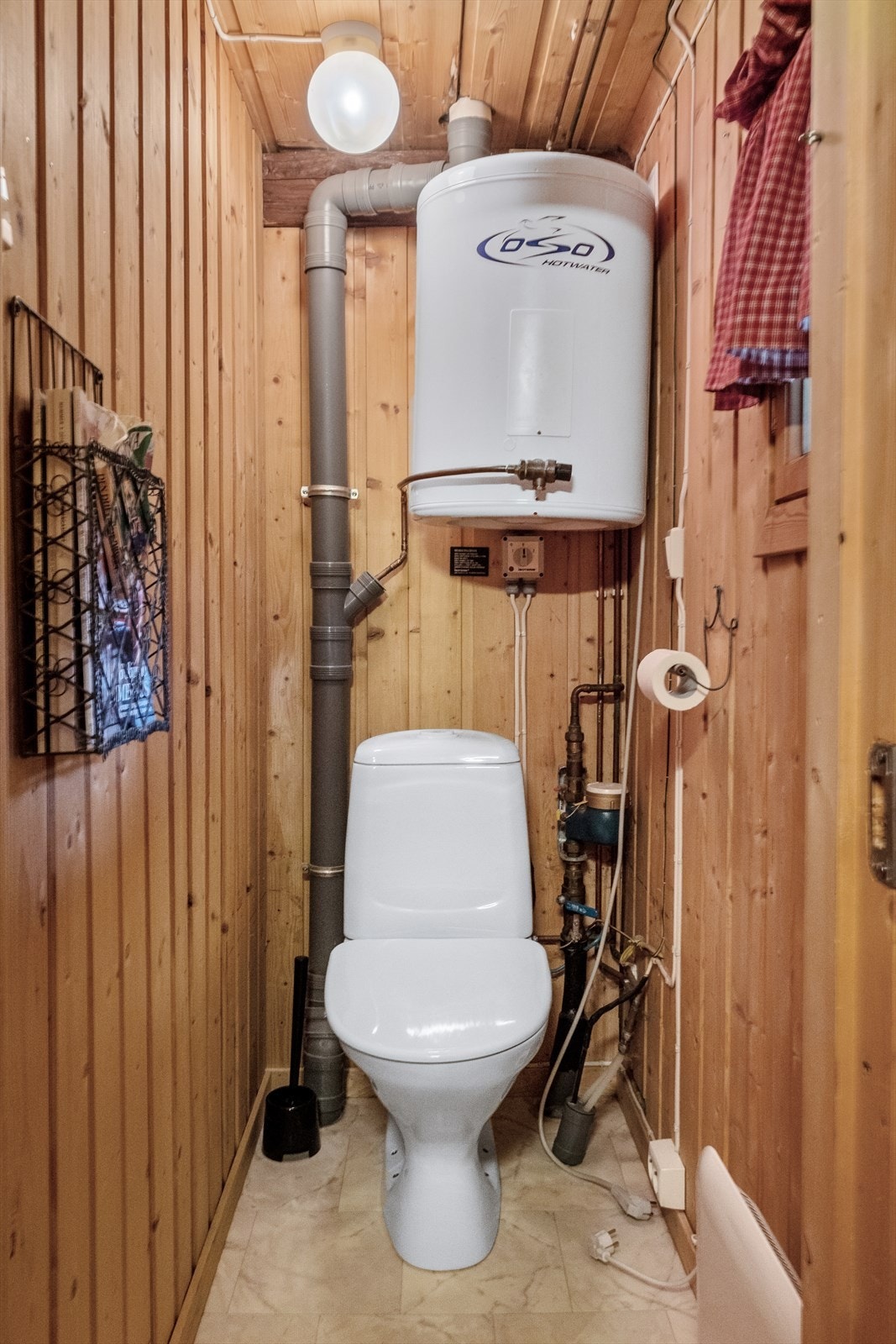 Toalettrom på badet med gulvbelegg og panel på vegger. Toalettrommet inneholder gulvmontert toalett og varmtvannsbereder. Galleribilde