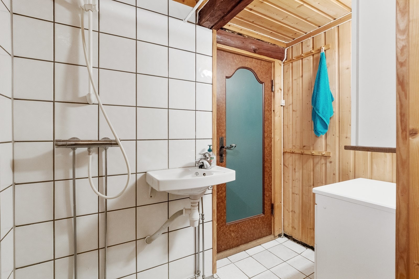 Lyst baderom med fliser på gulv og panel og fliser på vegger. Galleribilde