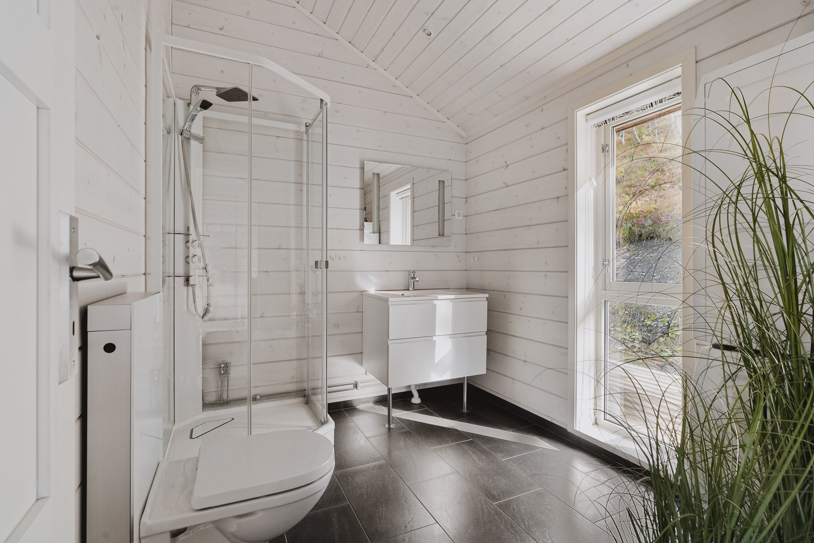 Romslig bad med moderne baderomsinnredning med mye oppbevaringsplass og overspeil.