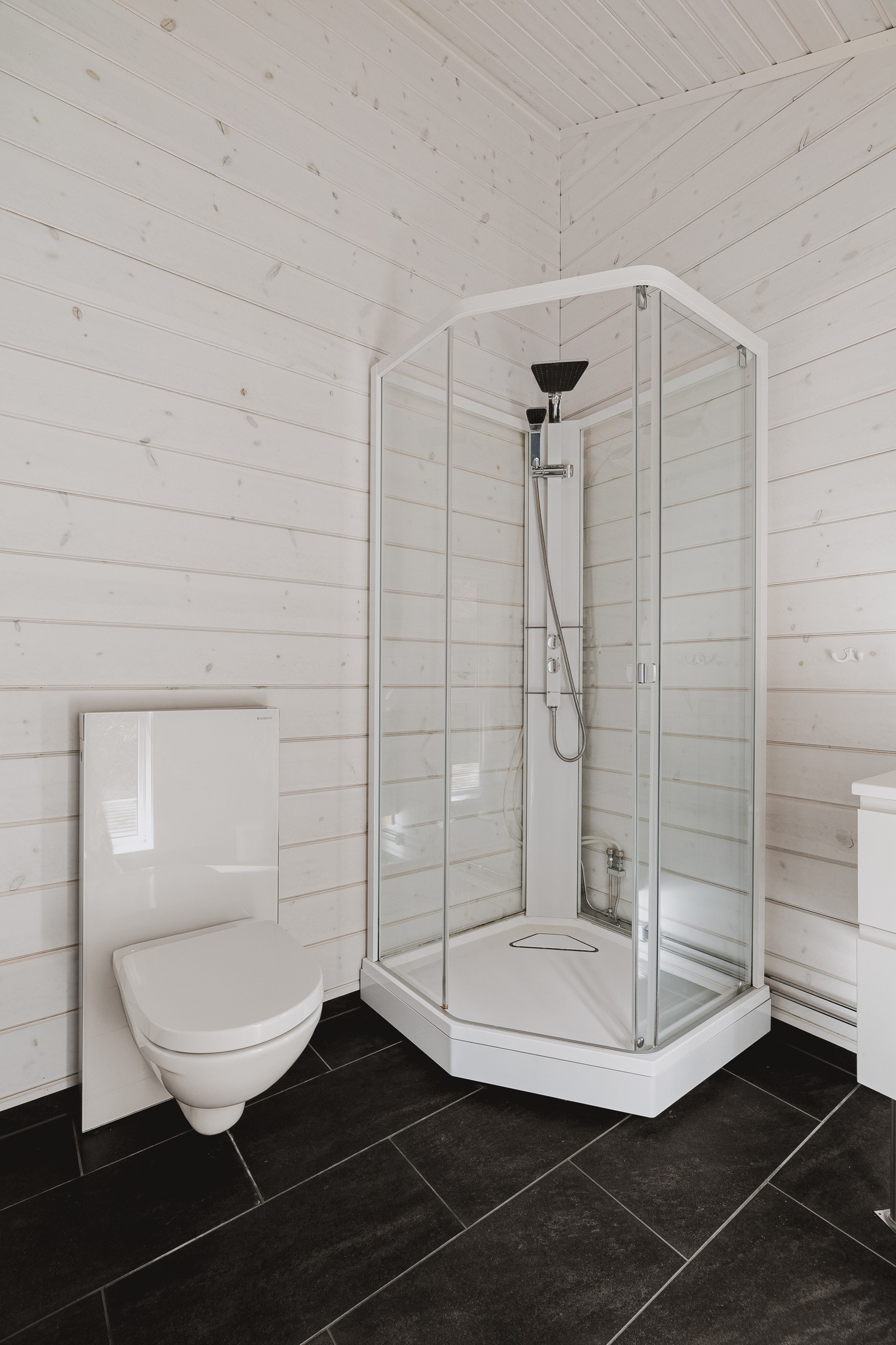 På badet er det dusjkabinett og vegghengt toalett.