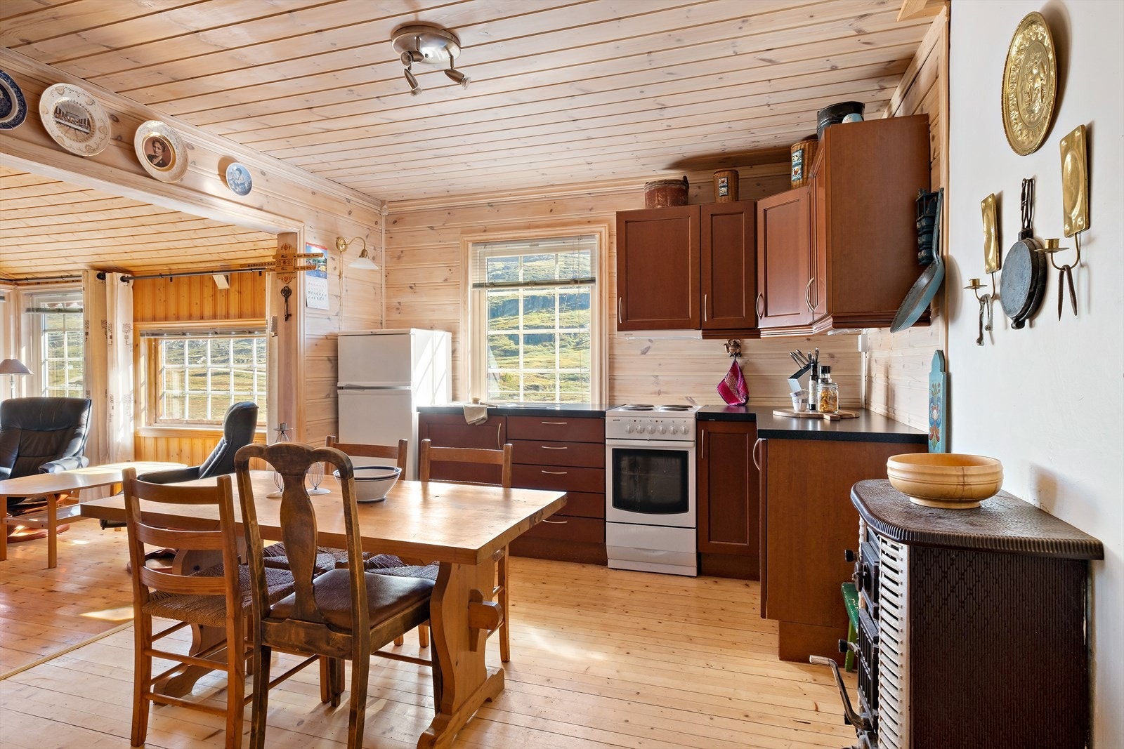 Stort og romsleg kjøkken. Vindauge slepp inn rikeleg med naturleg lys. Legg merke til vedovnen på kjøkkenet. Galleribilde