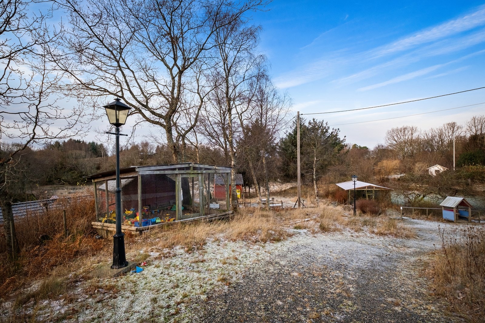 Lekeplass med overbygget og inngjerdet sandkasse og lekehytte. Galleribilde