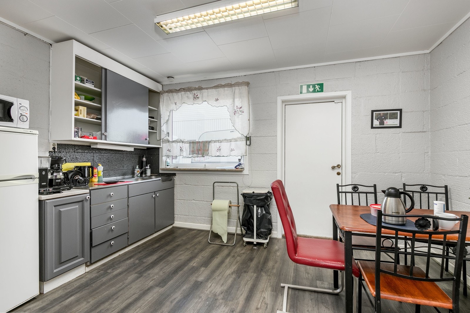 Kjøkkeninnredning med glatte fronter. Benkebeslag i rustfritt stål med utslagskum og kum. Galleribilde