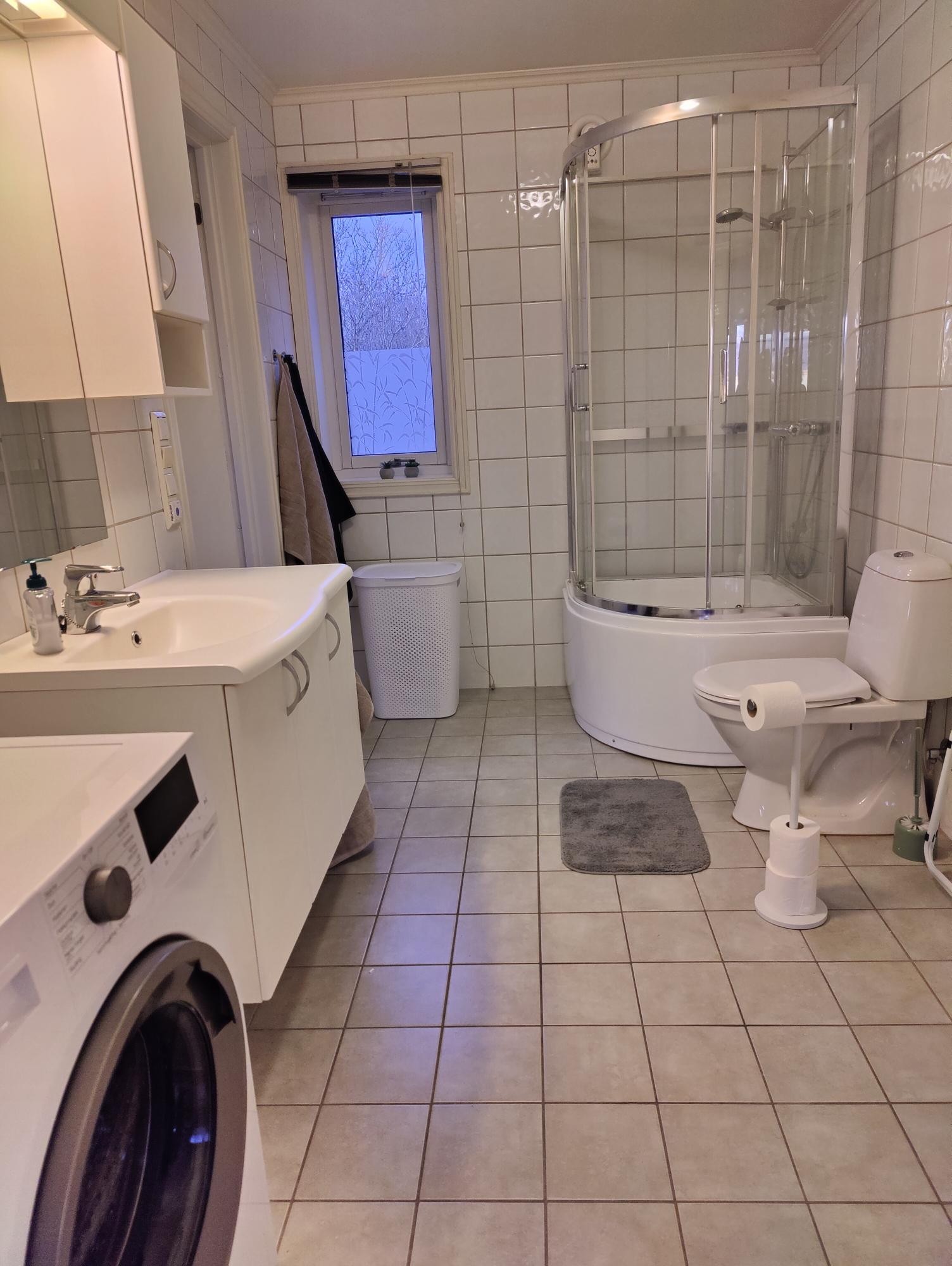 Lyst og trivelig bad med dusjkabinett og vaskemaskin Galleribilde