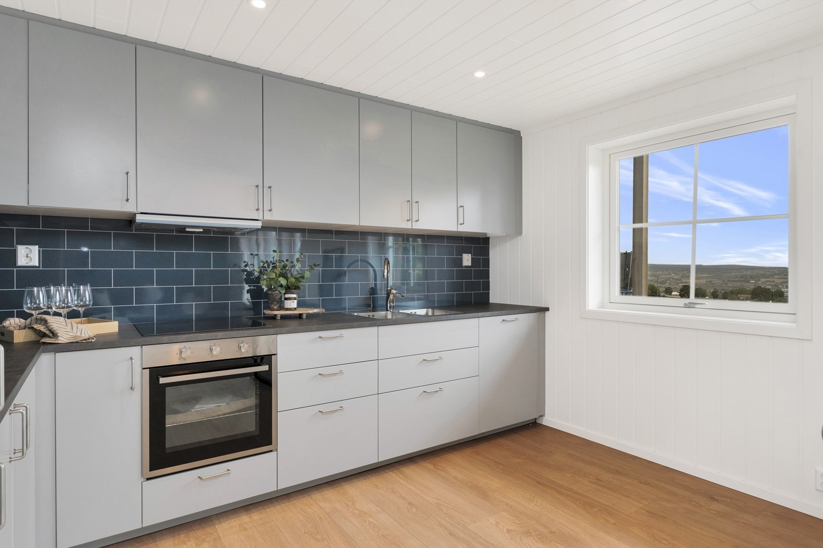 Kjøkkeninnredning i lyst grått. Integrert koketopp, stekeovn, kjøleskap og oppvaskmaskin. Bilder tatt i seksjon 3, avvik kan forekomme. Galleribilde