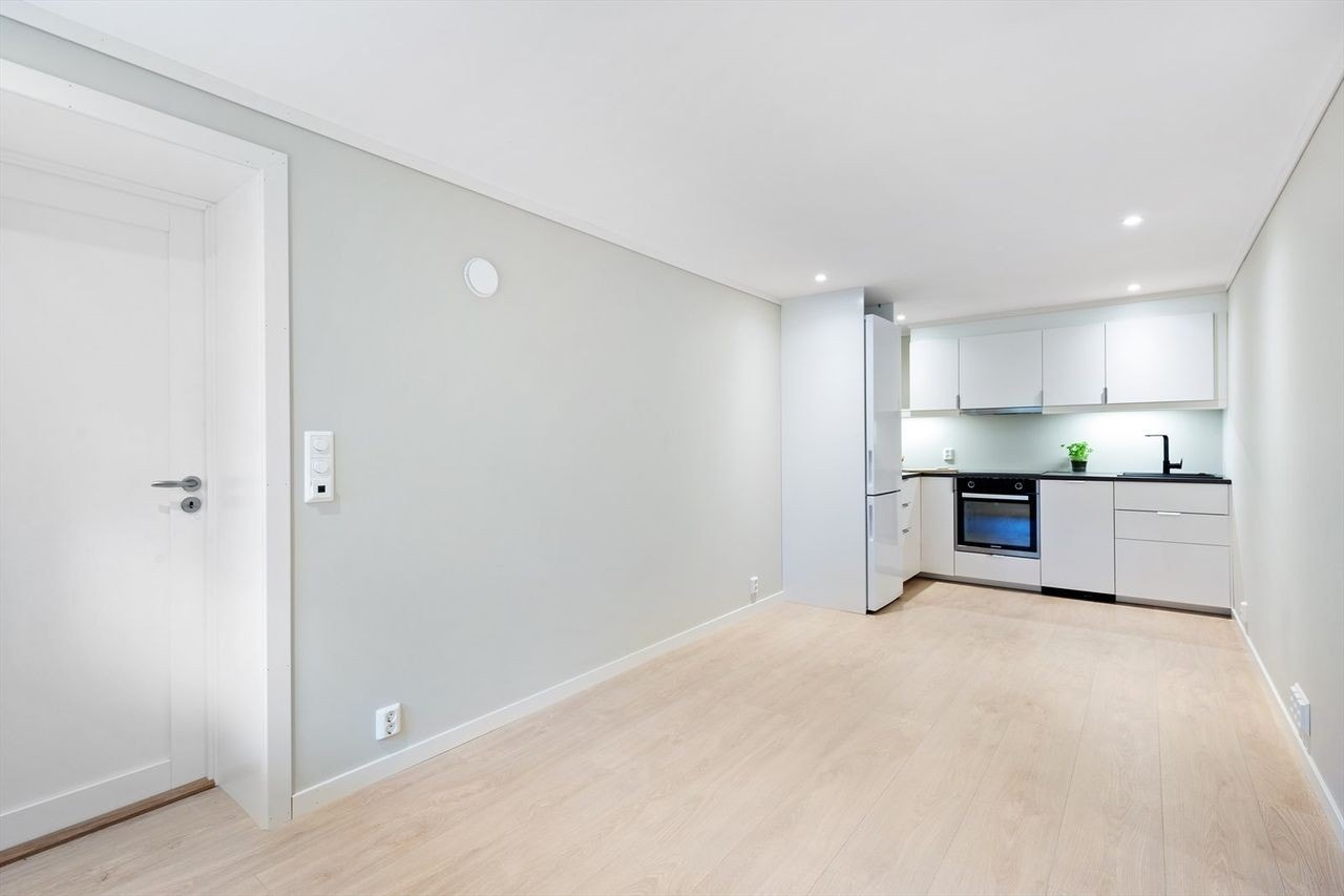 Romslig åpen stue og kjøkken løsning. Stuen er nå møblert med sofa og enkel skrivepult m/kontorstol. Galleribilde