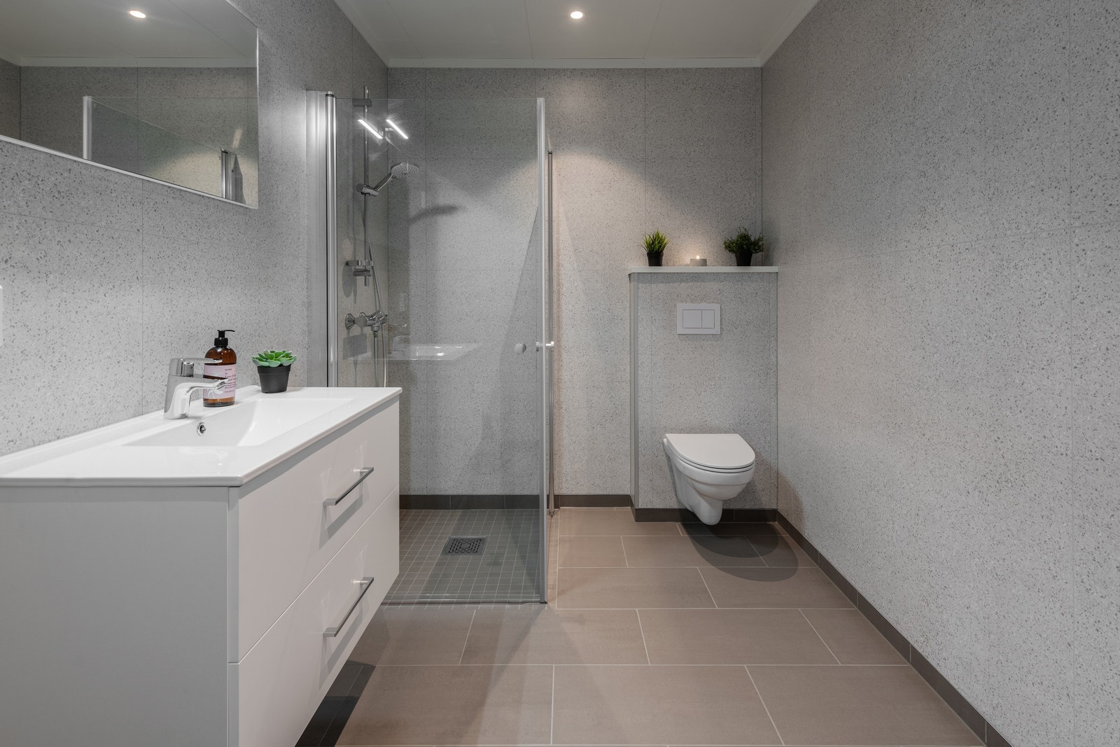 Lyst og fint bad med moderne og delikate baderomsplater. Det er også vegghengt toalett og spotter i tak. Galleribilde