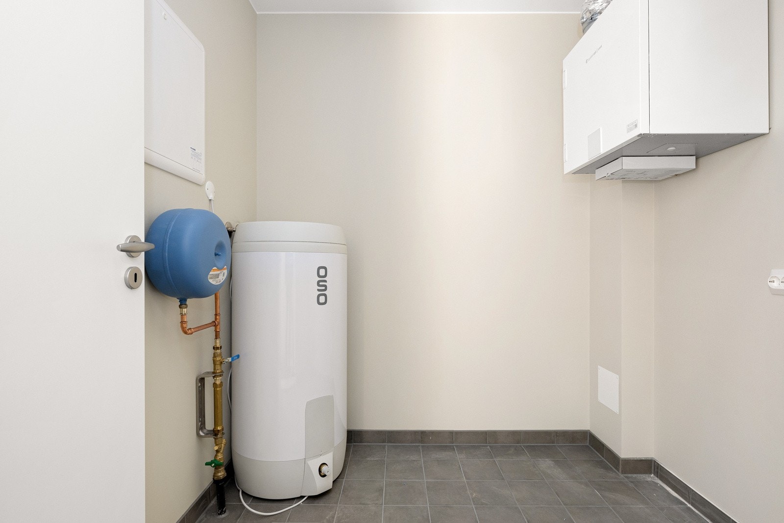 Tvers over gangen fra badet nede er det et teknisk rom med flislagt gulv, varmekabler og opplegg for vaskemaskin. Galleribilde