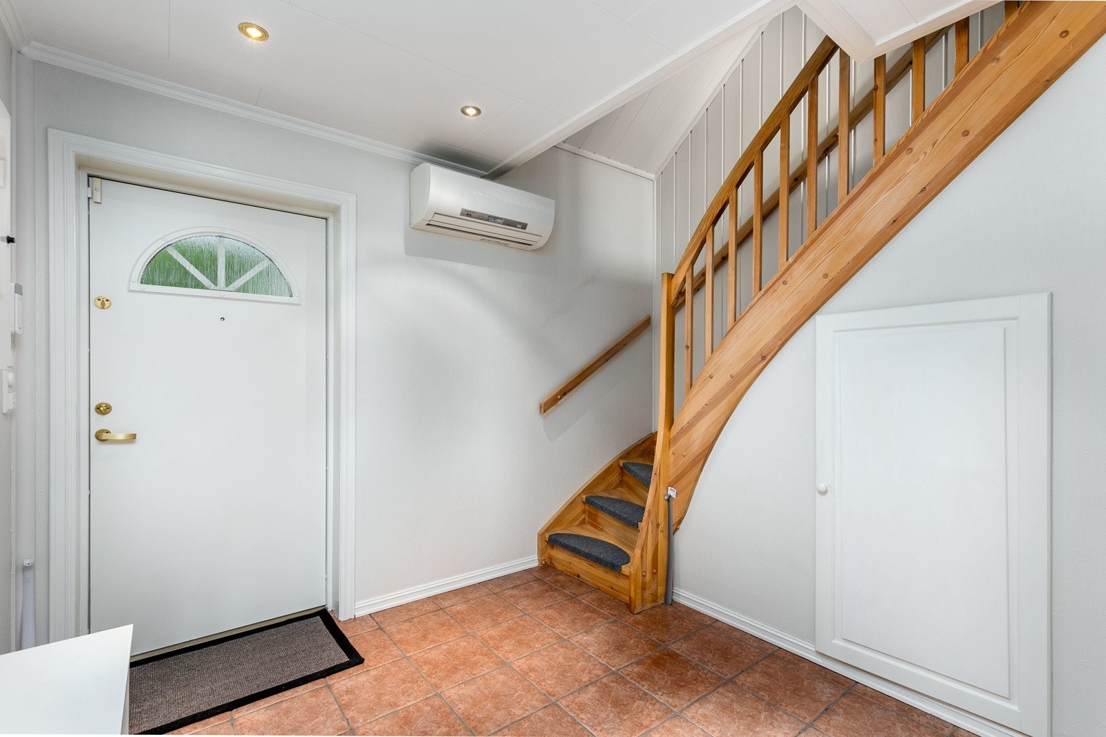 Romslig entre med lysmalte vegger og fliser på gulv. Det er mulighet for garderobeløsning etter eget ønske. Himlingen er pent lyssatt med downlights. Lagringsmuligheter under trappen. Det er montert luft til luft varmepumpe på veggen. Galleribilde
