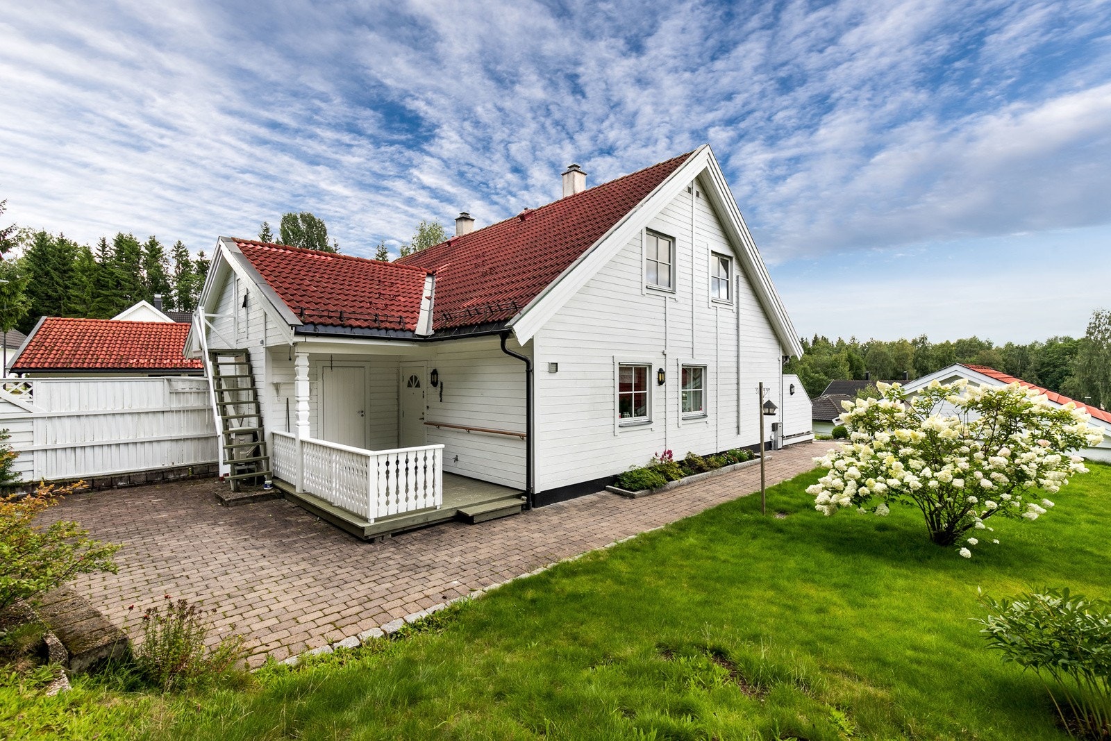 Meget pent opparbeidet tomt med prydbusker, beplantning, plenarealer og partier belagt med belegningsstein. Galleribilde