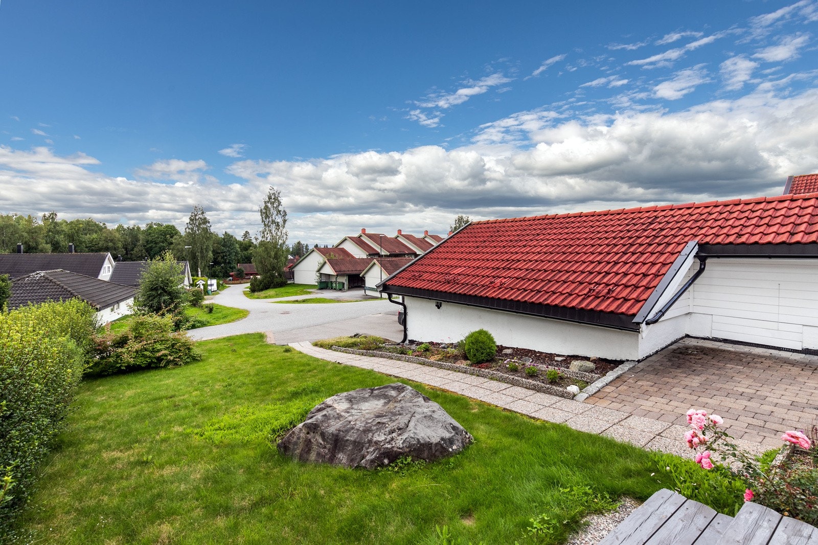 Meget pent opparbeidet tomt med prydbusker, beplantning, plenarealer og partier belagt med belegningsstein. Galleribilde