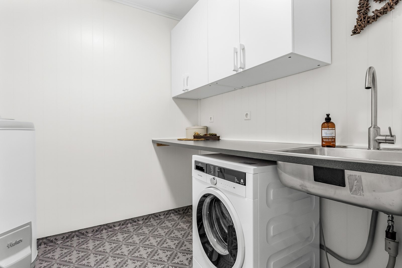 Praktisk, separat vaskerom med opplegg for vaskemaskin og tørketrommel. Det er innredet med overskap, benkeplate og vask. Varmtvannstank på ca. 200L. Galleribilde