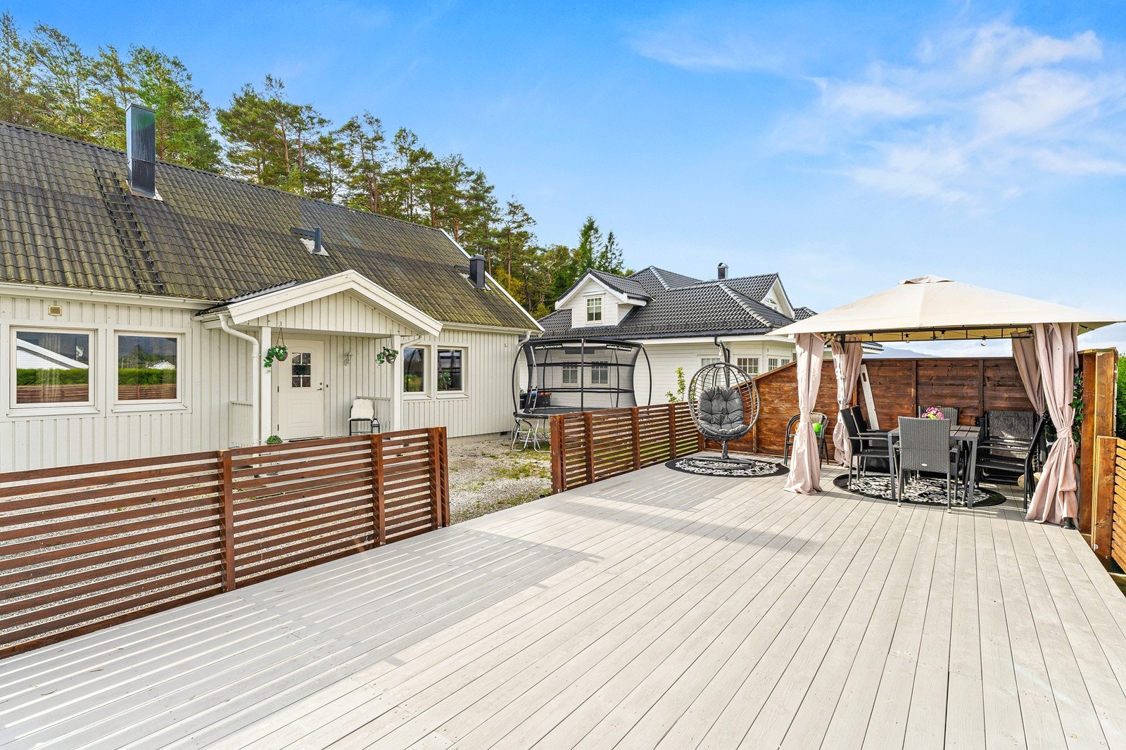 Totmen er pent opparbeidet med gruset adkomst og tun, store terrasser og en liten plen. Galleribilde