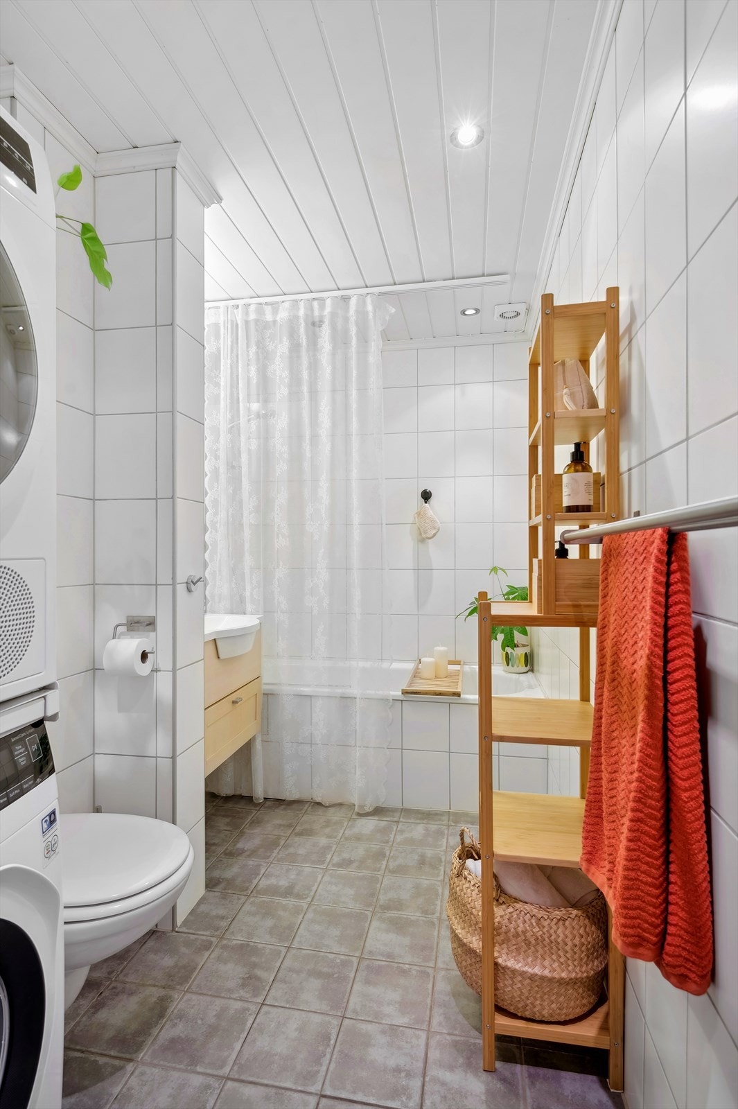 Badet er helfliset og oppvarmet med elektriske varmekabler - Rommet har vegghengt toalett, badekar m/dusjgarnityr på vegg, opplegg for vaskemaskin og baderomsinnredning Galleribilde