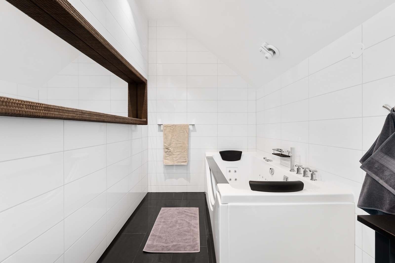 Badet er utstyrt med vegghengt toalett, dobbel servantinnredning og veggmontert speil, samt boblebad Galleribilde