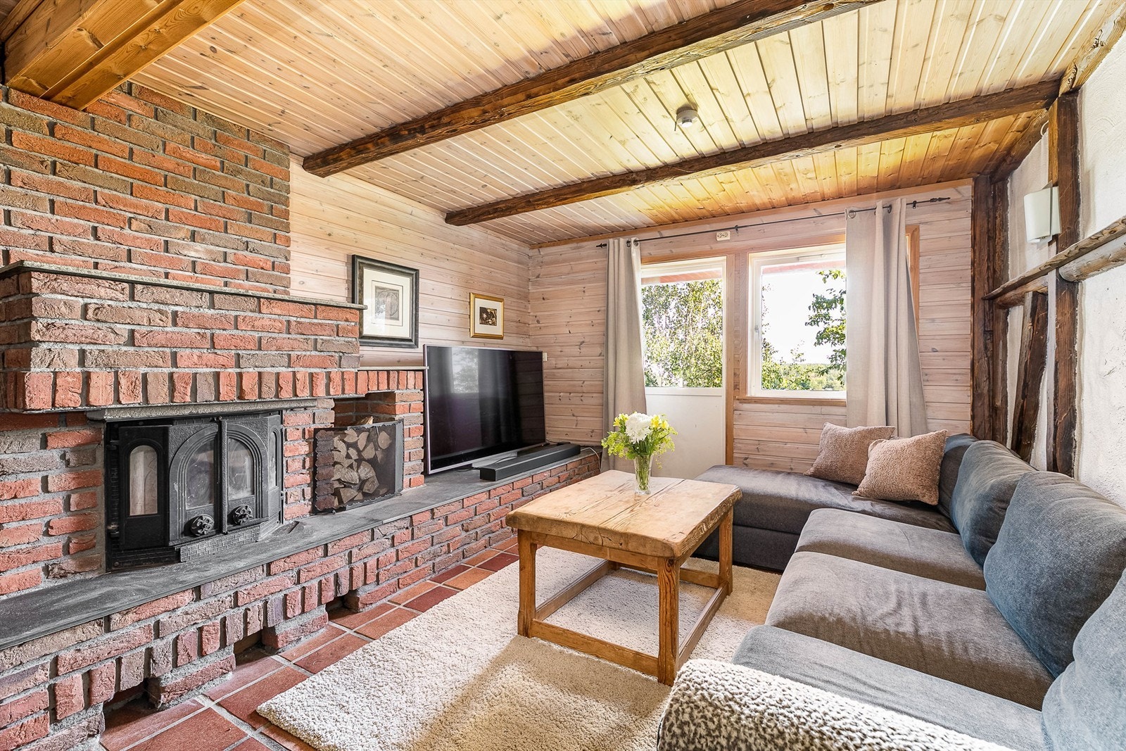 Peisstue med rustikk atmosfære og utgang til skiferbelagt platting i hagen. Galleribilde