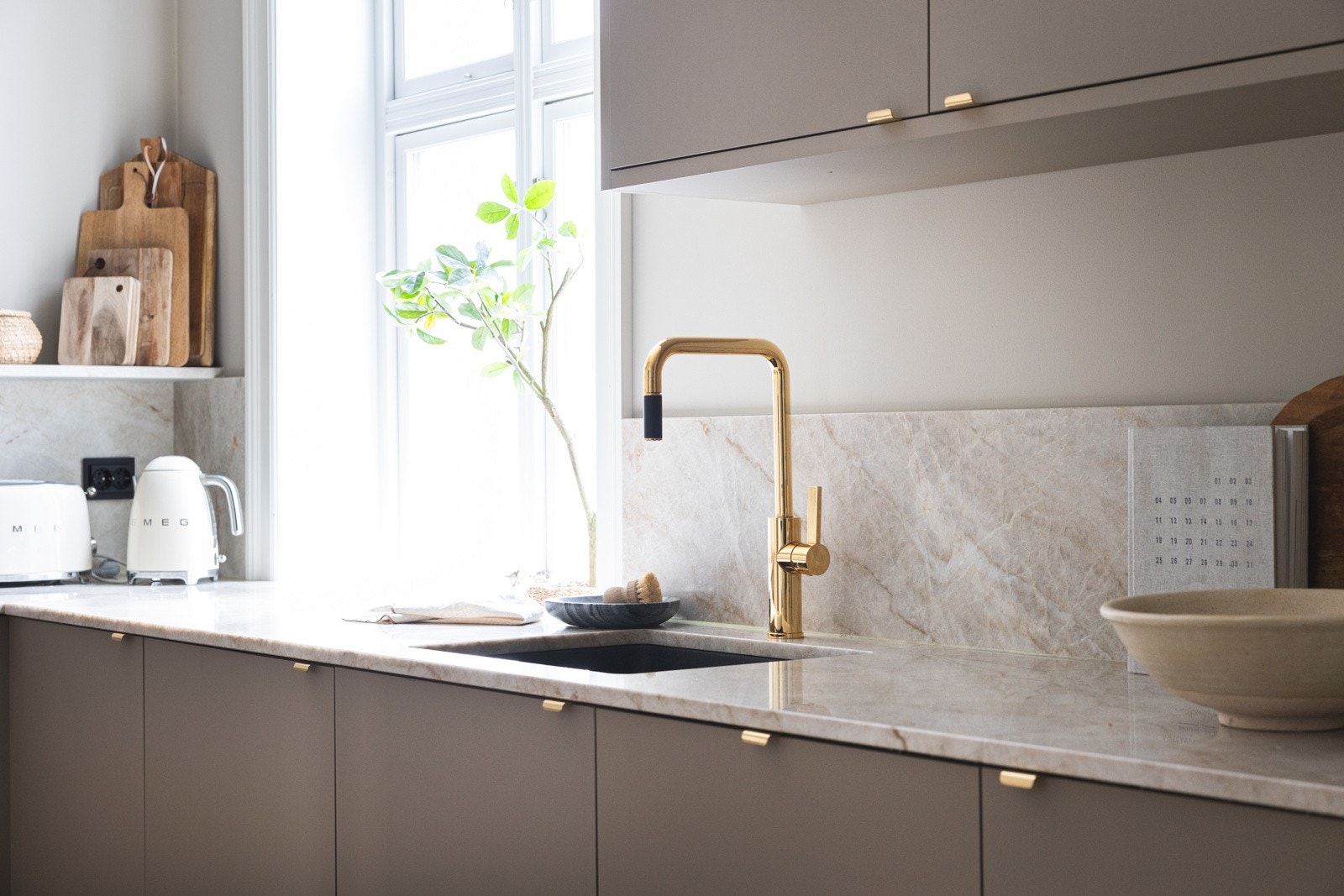 Kjøkkenet har glatte fronter, samt benkeplate av komposittstein i fargen Taj Mahal, med backsplash på vegg og hylle i samme materiale. Galleribilde