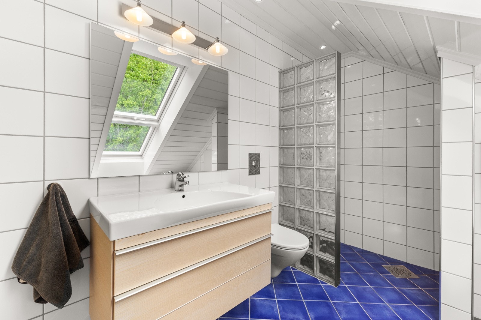 Pent flislagt bad med moderne innredning og takvindu som slipper inn godt med dagslys. Galleribilde