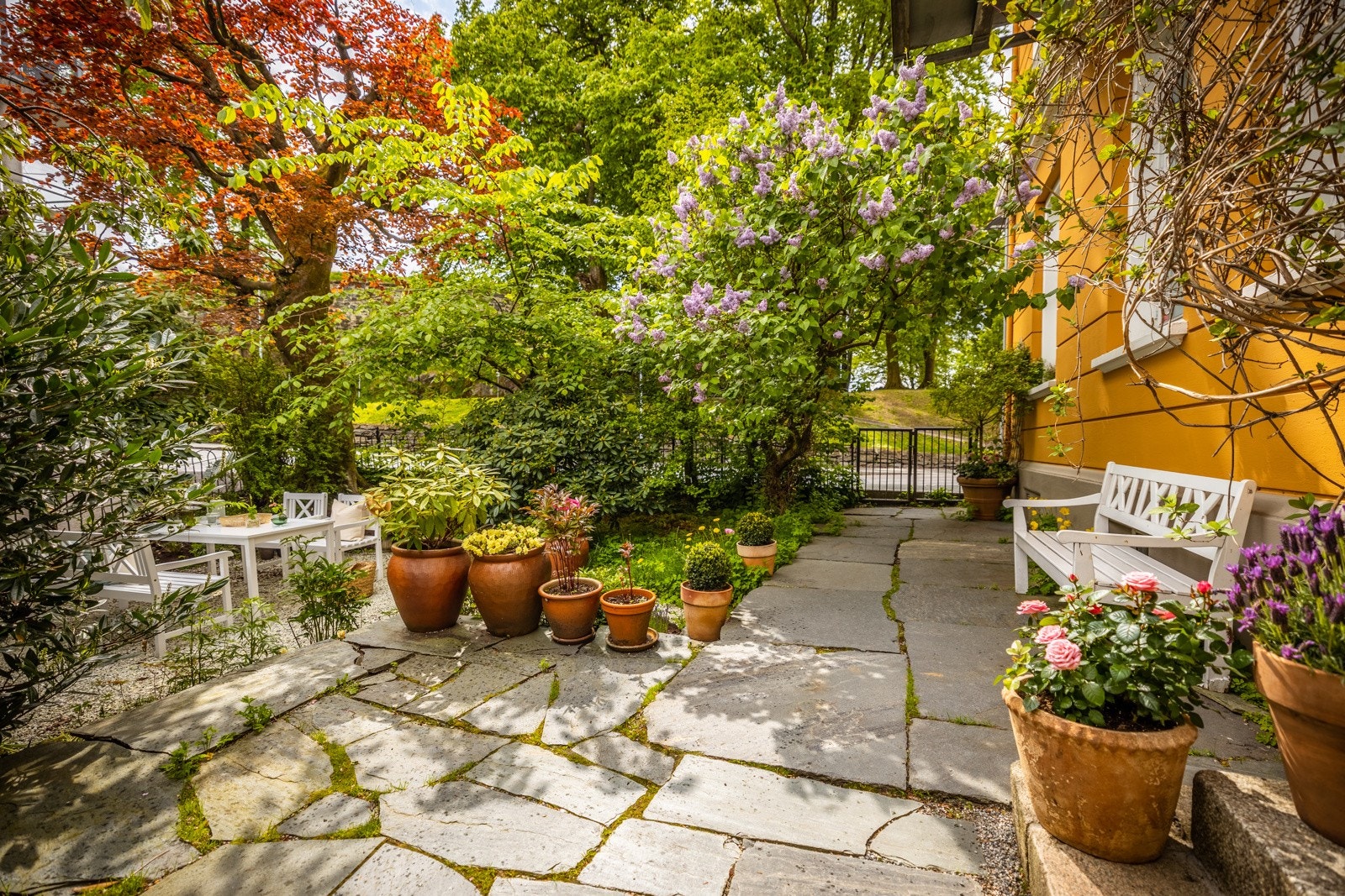 Uteplassen er opparbeidet over mange år og her blomstrer det gjennom vår og sommer. Galleribilde