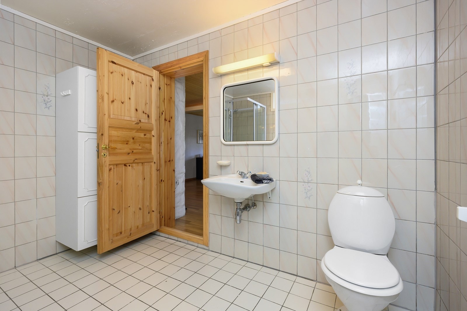 Badet inneholder dusjkabinett, servant, baderomsmøbler for oppbevaring, frittstående wc og opplegg for vaskemaskin. Galleribilde