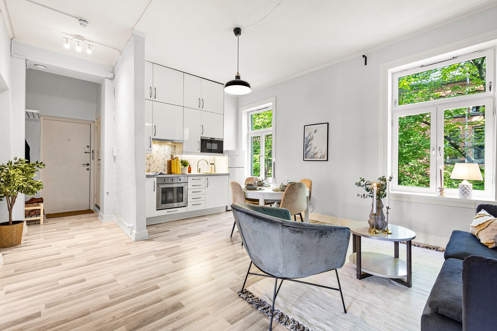 Lys og romslig stue med åpen kjøkkenløsning og store vindusoverflater inn mot grønne fellesarealer. Galleribilde