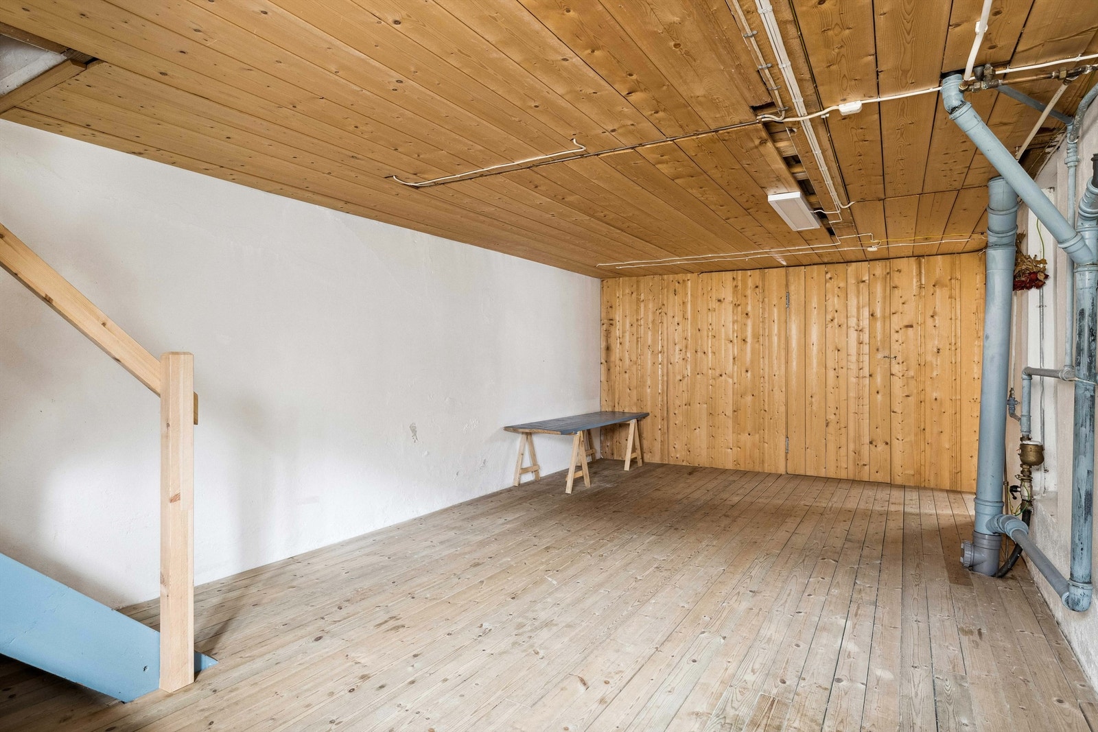 Kjellerrom med tregulv og panel og betong på veggene. Galleribilde