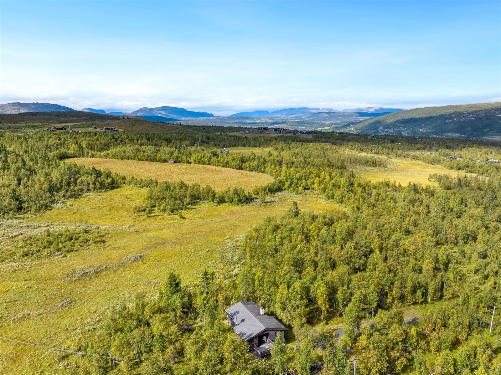 Eiendommer ligger på naturtomt i skrående terreng ved lauvskog i fjellterreng. Galleribilde