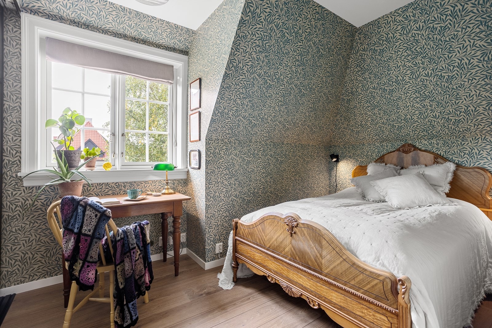 Et lyst og luftig soverom med plass til dobbeltseng og tilhørende møblement. Soverommet er tapetsert med tapet fra William Morris. Galleribilde
