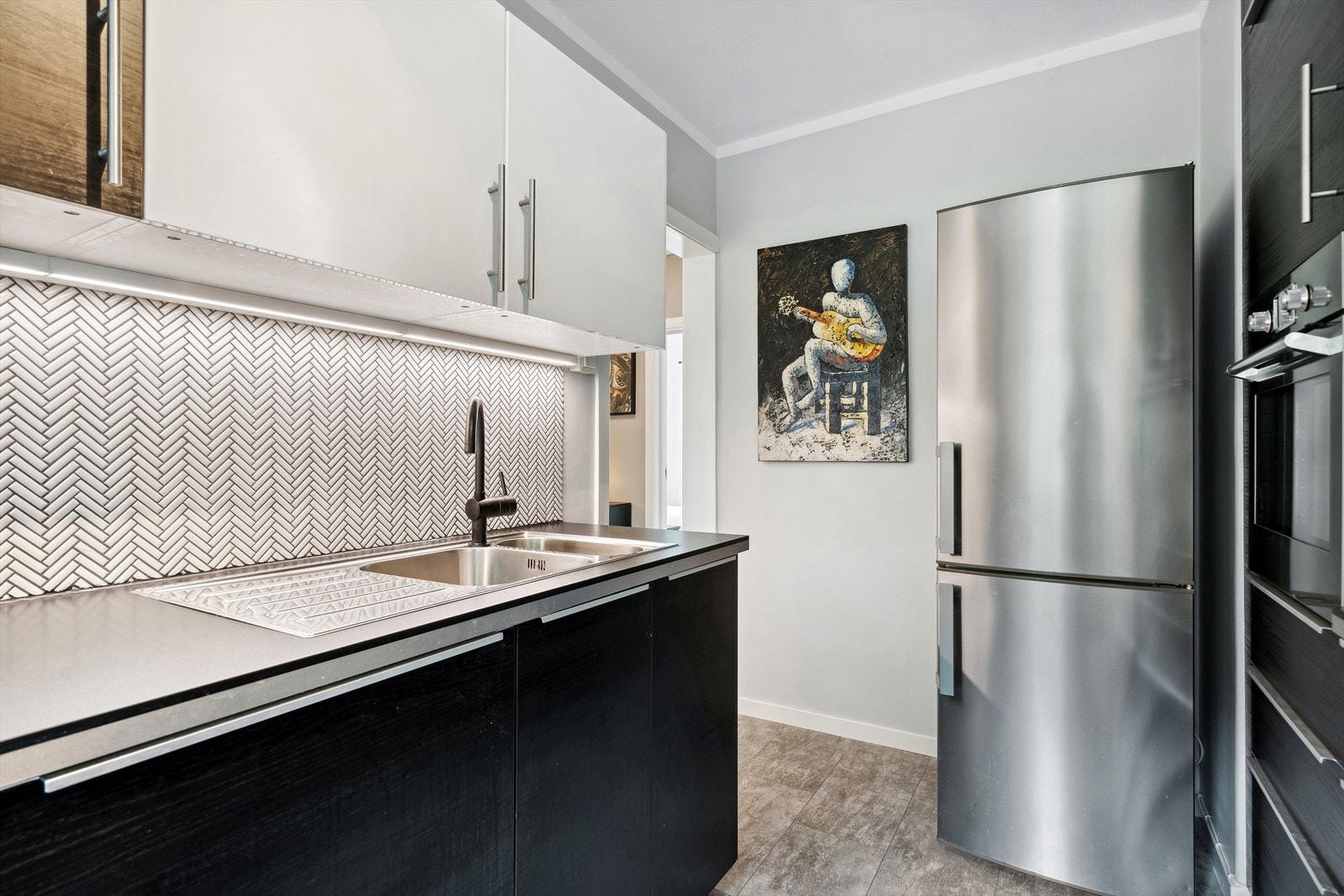 Hvitevarer: Stekeovn i veggmodell fra 2022, oppvaskmaskin, keramisk topp og frittstående kjøl- og fryseskap. Galleribilde