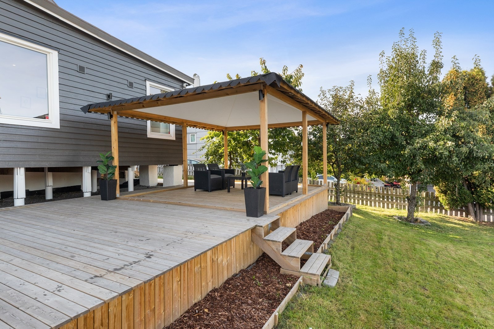Pent opparbeidet tomt med stor terrasse, plen og beplantninger. Galleribilde