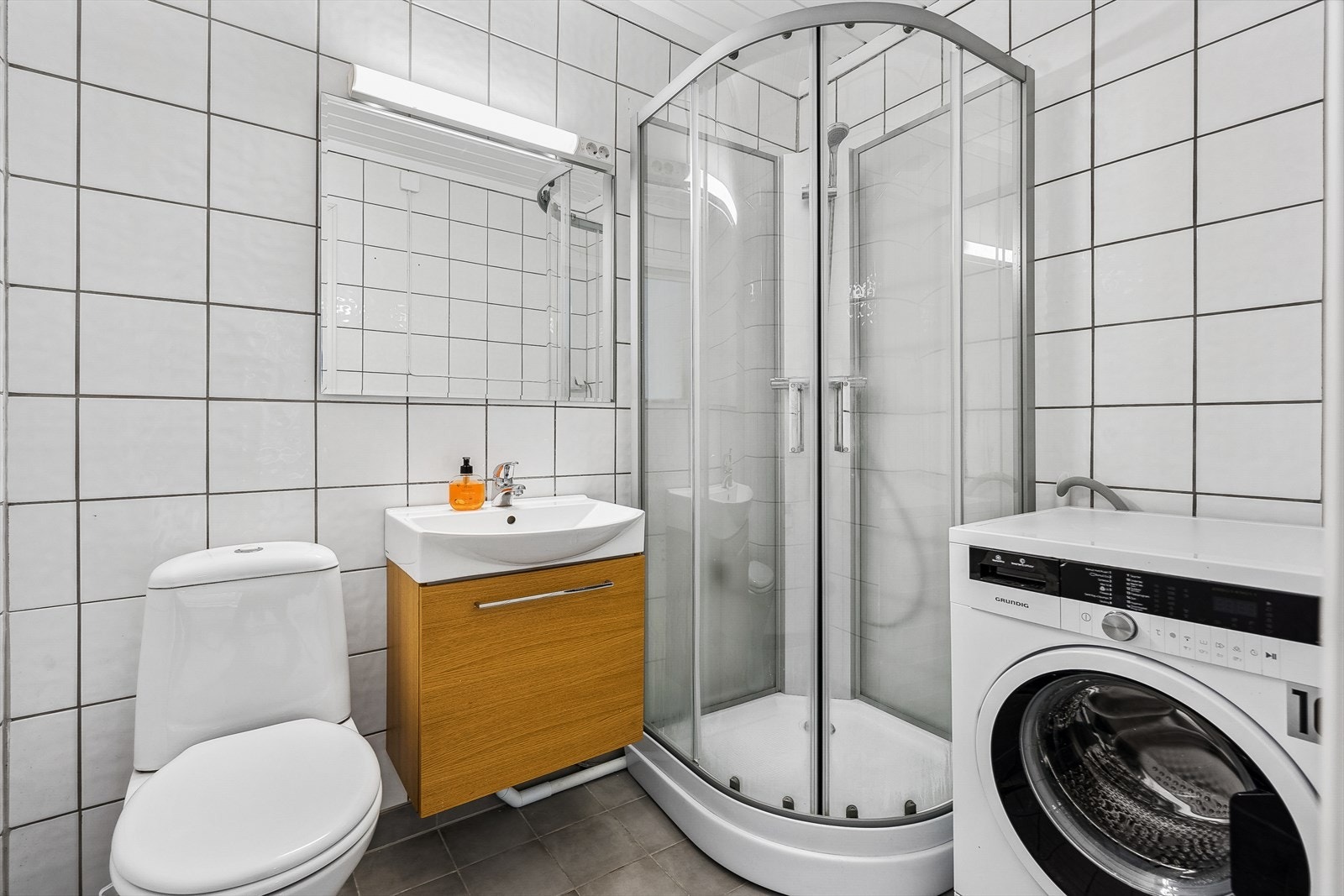 Pent flislagt bad med varmekabler i gulv og opplegg for vaskemaskin. Det er også felles vaskerom i kjeller. Galleribilde