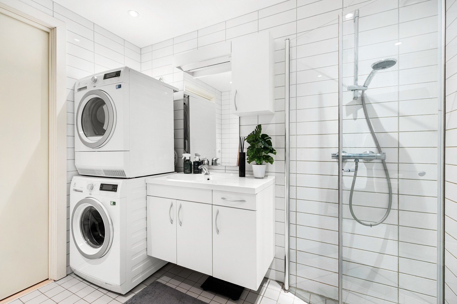 Badet har vegghengt servantskap med heldekkende servant og ett-greps armatur, overskap og speil og opplegg for vaskemaskin og tørketrommel. Galleribilde