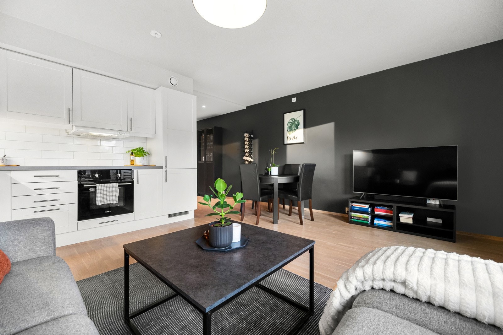 Stuen har flotte kontraster mellom varmen i parketten og den hvite inredningen mot de ellers sorte veggene. Galleribilde