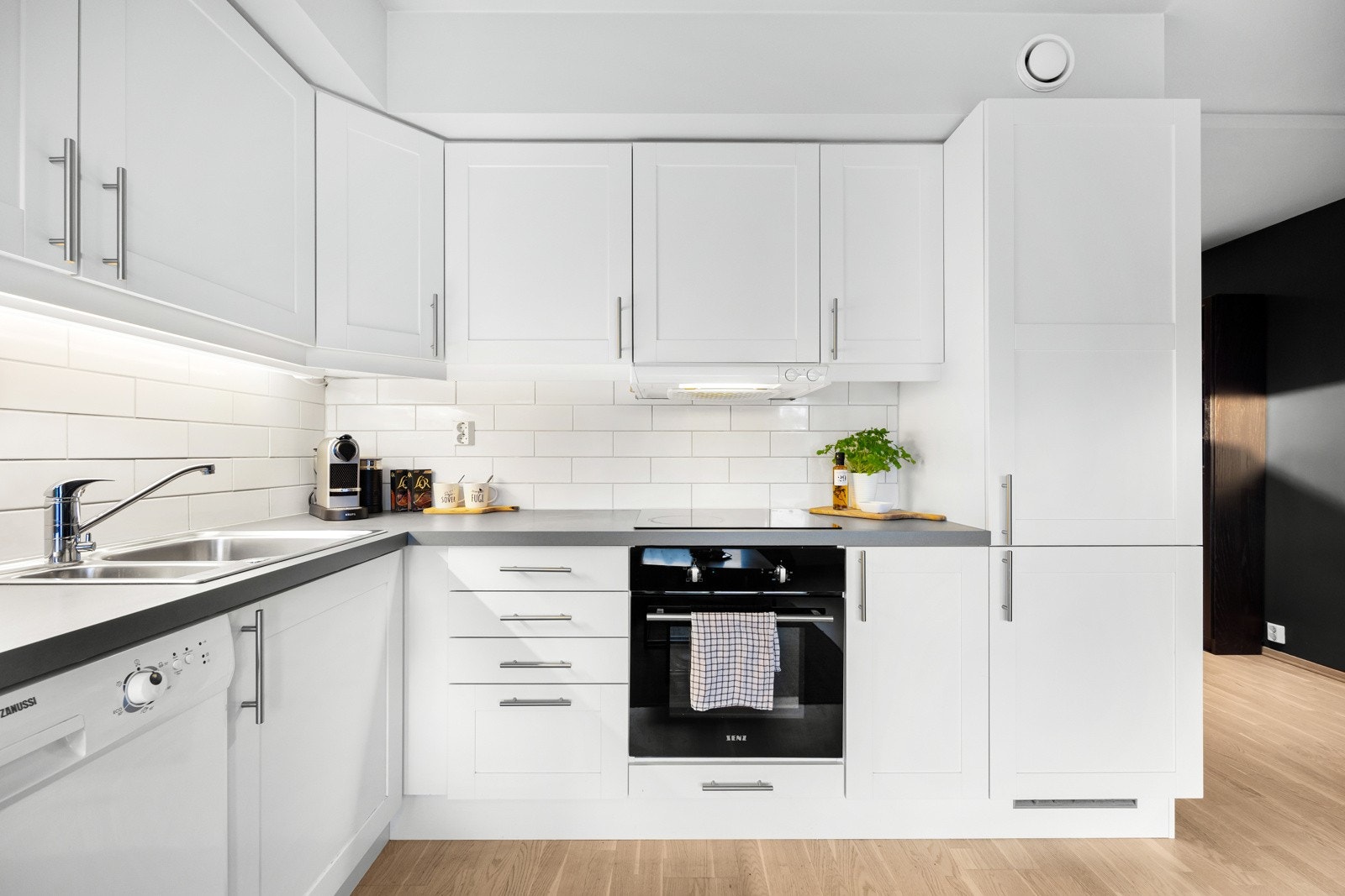 Kjøkkenet har hvite slette fronter og benkeplate i laminat som både er praktisk og enkelt å holde rent. Galleribilde