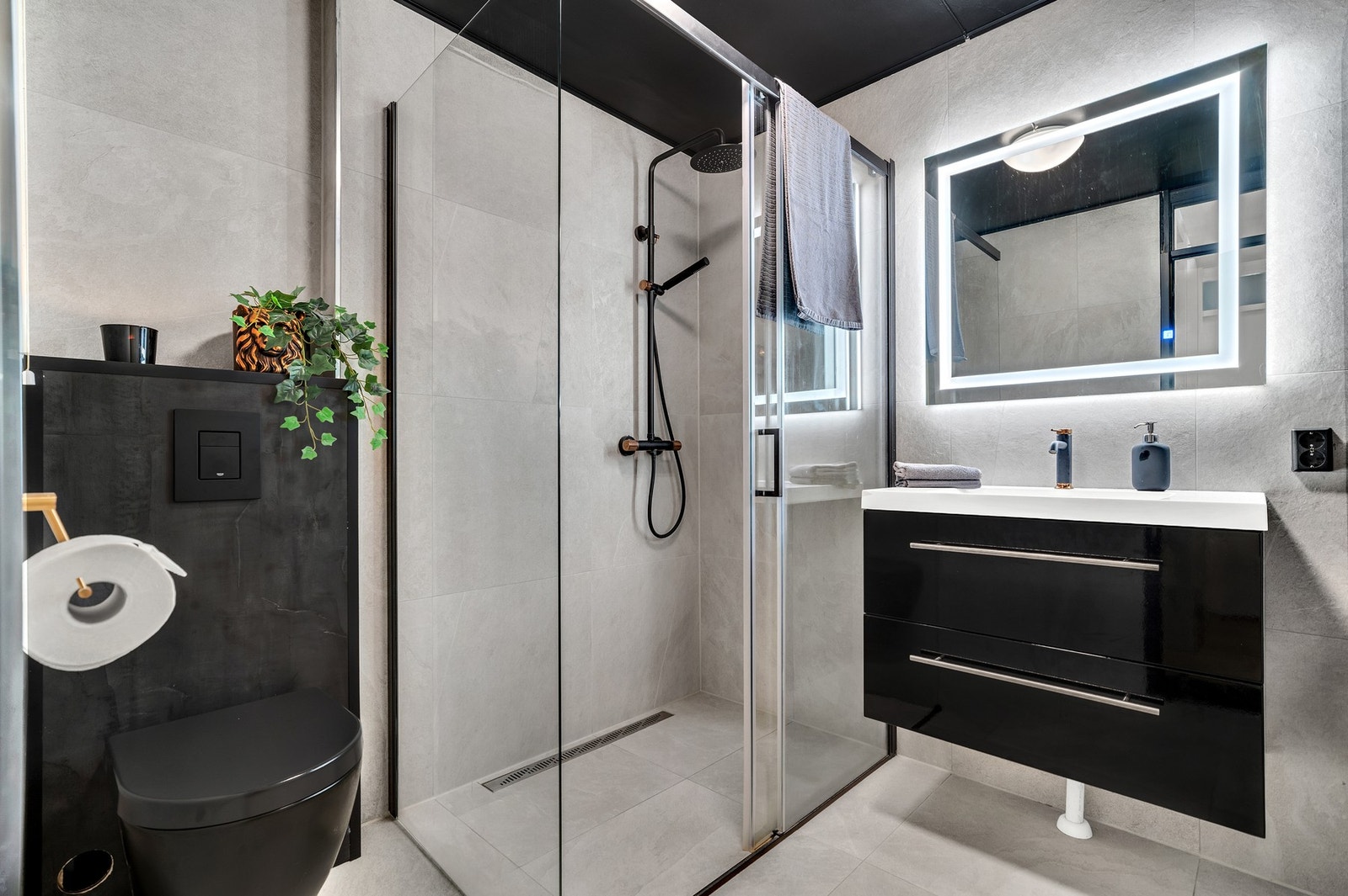 Delikat og flislagt baderom fra 2022. Innbydende dusjnisje i sorte detaljer. Galleribilde