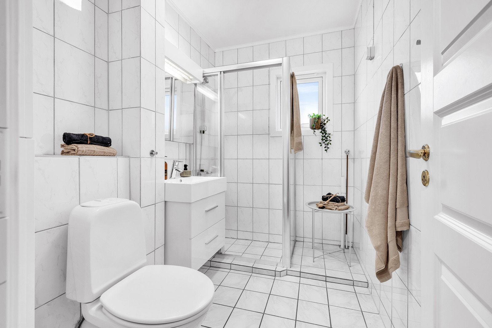 Flislagt baderom med gulvvarme, innredet med servantskap, speilskap m/ tilhørende lys, wc, og dusjhjørne med skyvedører. Galleribilde