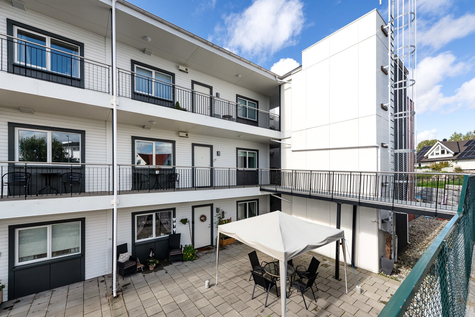 På inngangssiden er det en hellelagt markterrasse terrasseplatting hvor det er anlagt felles sittebenker. Galleribilde