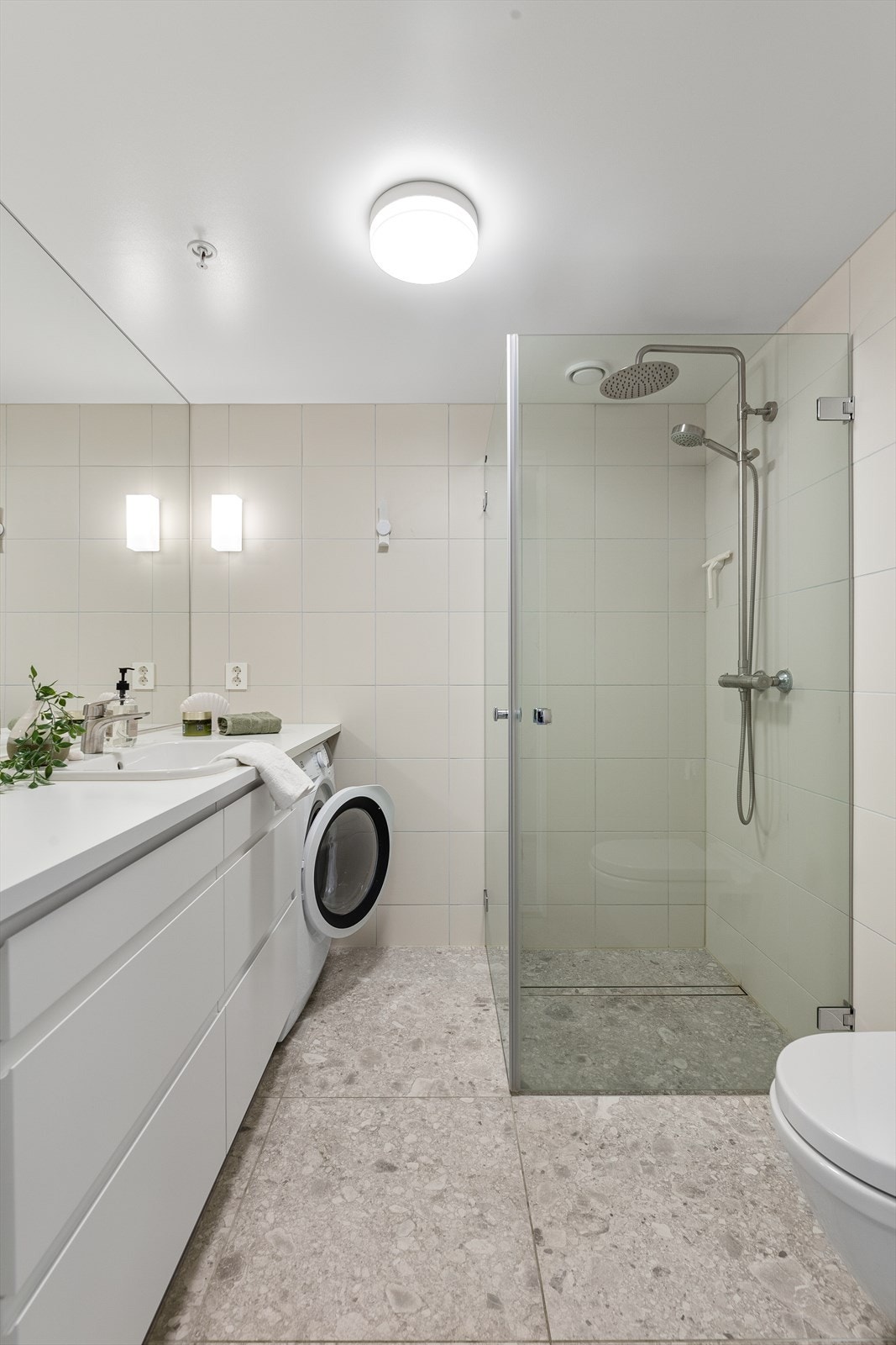 Badet har dusjhjørne med foldedører av glass og regnfallsdusj Galleribilde