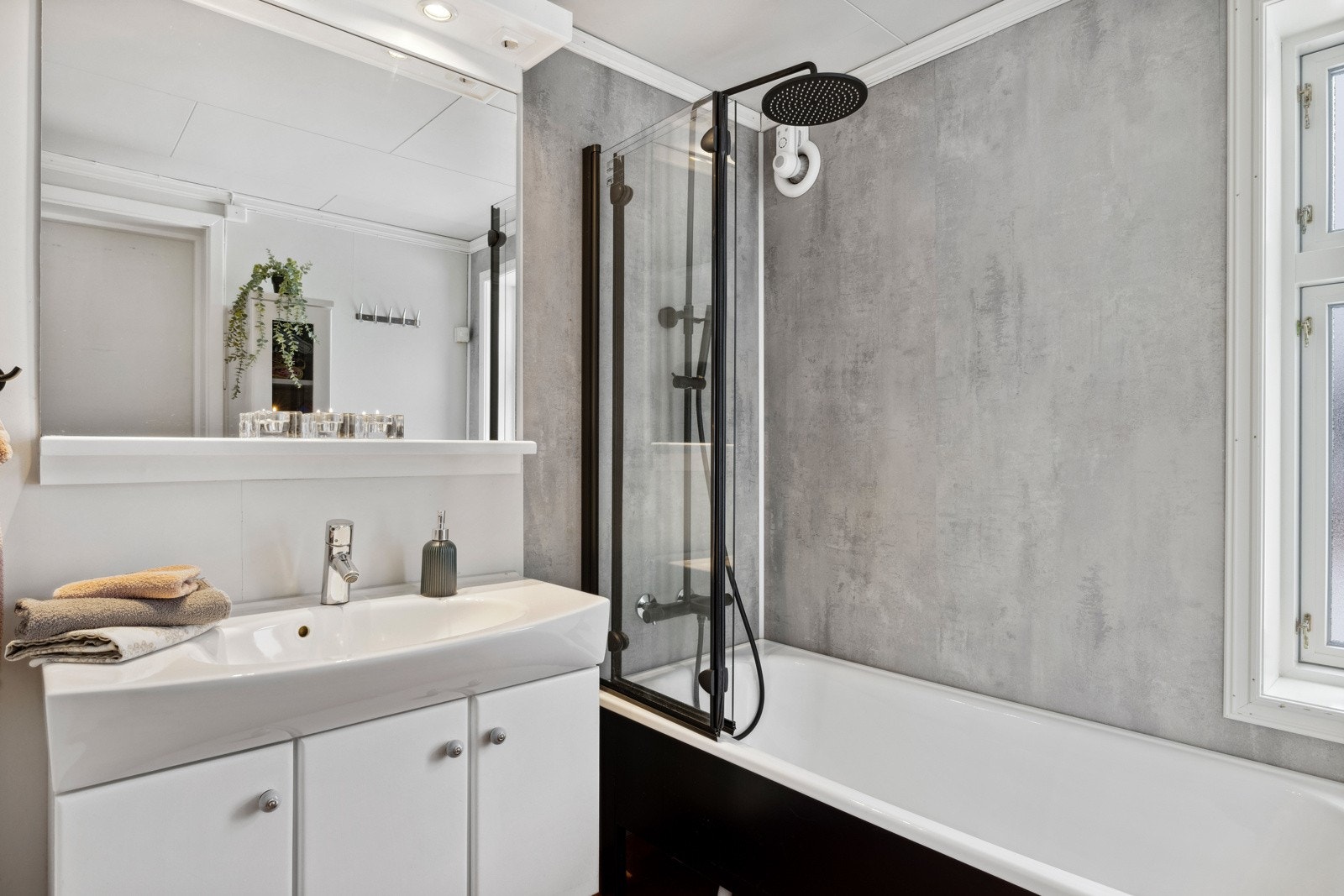 Baderommet er også utstyrt med badekar med glassdør og sort vegghengt dusj med både hånd- og regnfallsdusj, samt gulvmontert toalett. Elektrisk styrt vifte fra 2021. Galleribilde