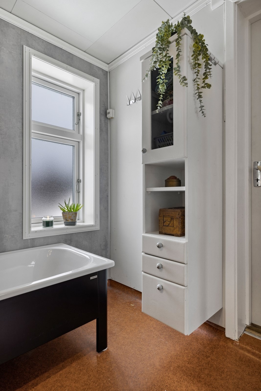 Boligen har et lyst baderom med varierende alder og bruksslitasje. Baderommet har våtromsbelegg på gulv med gulvvarme, malte våtromsplater på veggene og nyere våtromsplater fra 2021 i våtsonen. Galleribilde