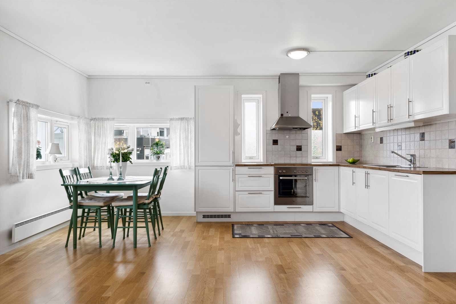 Kjøkkenet har en tidløs innredning i hvitt, oppført i en funksjonell hjørneløsning med god arbeidsflyt. Galleribilde