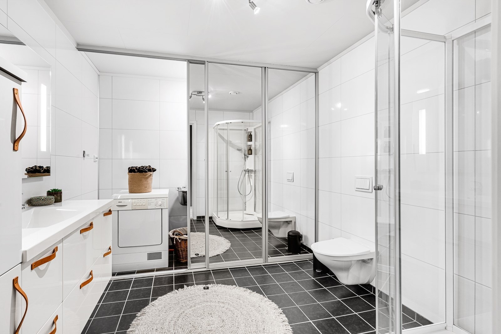 Badet er tidløst, med skyvedør i speil til vaskemaskinen. Galleribilde