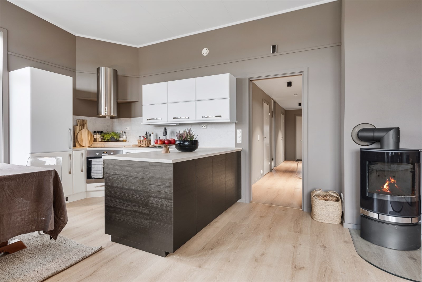 Kjøkkenet er utført med glatte fronter, laminert benkeplate fra ca. 2021. Det er kjøl/fryseskap, oppvaskmaskin, komfyr og platetopp. Galleribilde