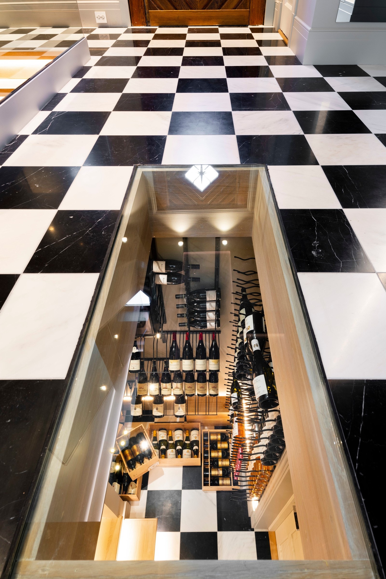 Boligen har en innbydende entré/hall i 1. etasje. Her er det flere plassbygde garderobeskap, samt et unikt gulv med sjakkmønstret fliser og glassgulv ned mot vinrommet i kjelleretasjen. Galleribilde