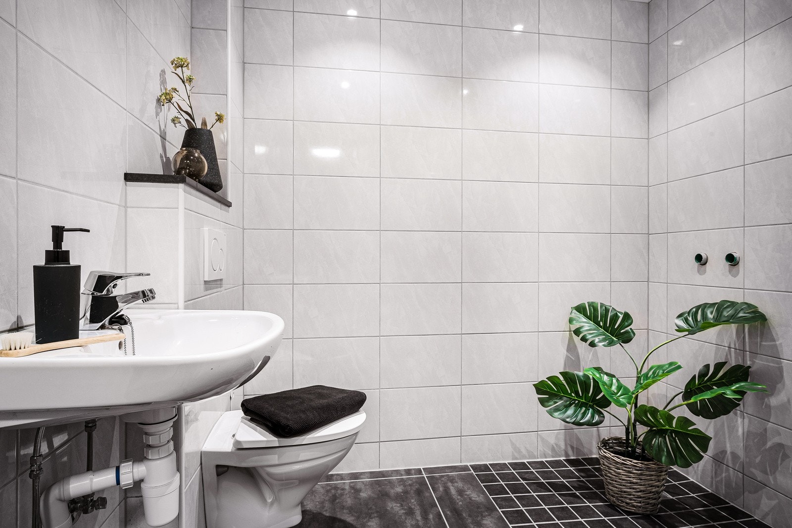 Badet er helfliset og innredet med servant og vegghengt toalett. Det er lagt opp til å kunne ha dusj i hjørnet. Galleribilde