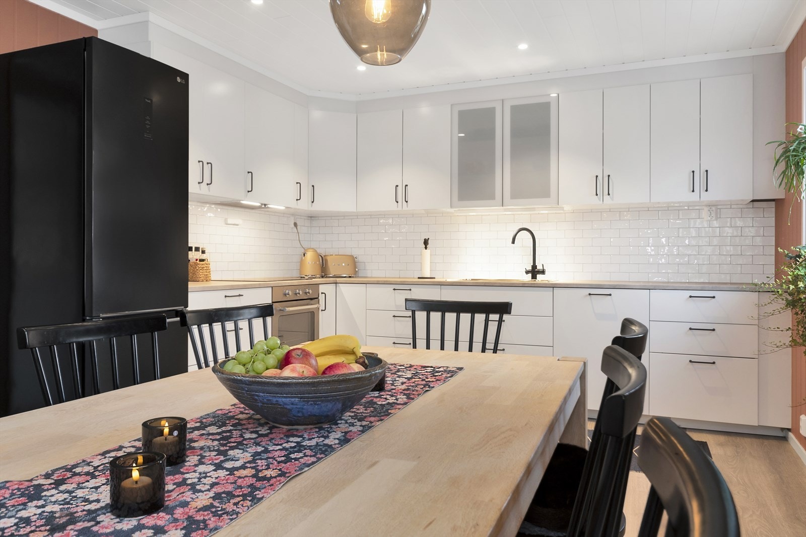 Kjøkkeninnredning fra IKEA med hvite, glatte fronter og benkeplate i laminat. Flislagt og belysning over benkeplate. Integrert komfyr, koketopp og oppvaskmaskin. Plass til frittstående kjøleskap. Komfyrvakt. Kjøkkenventilator er montert over komfyr. Galleribilde