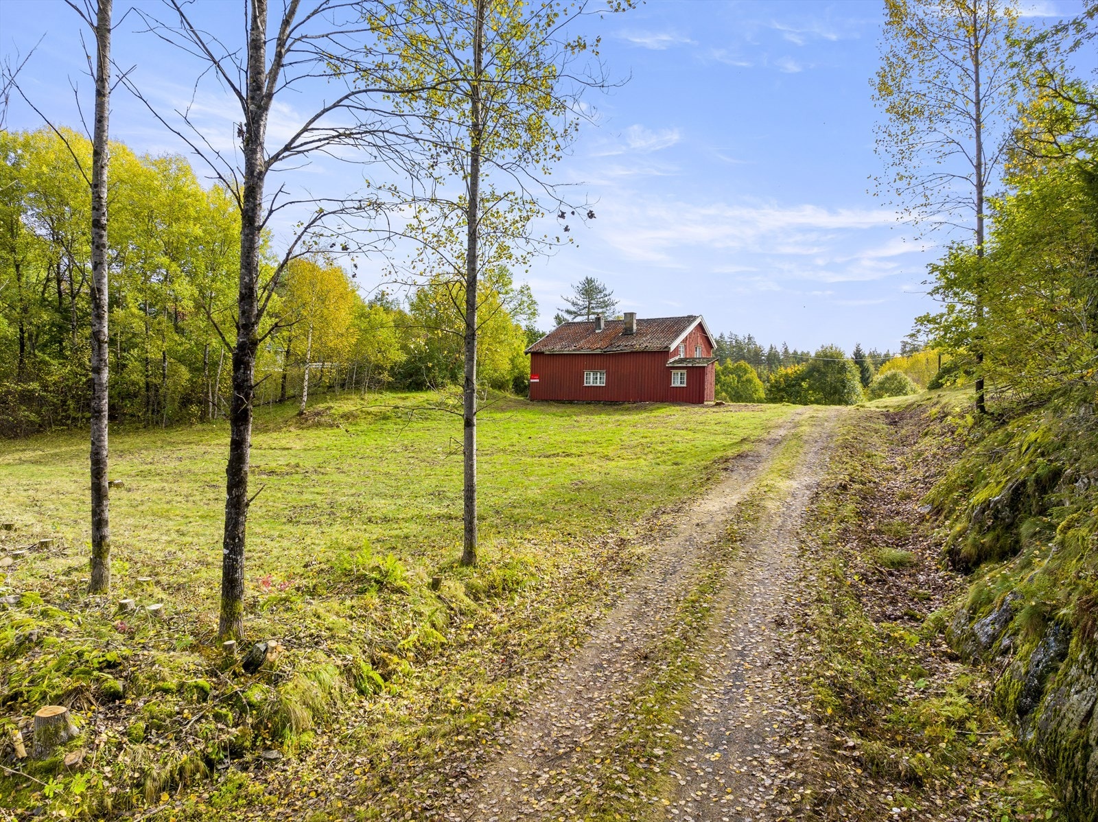 Boligen ligger på en høyde hvor eiendommen strekker seg til Båslandsveien på begge sider. Galleribilde
