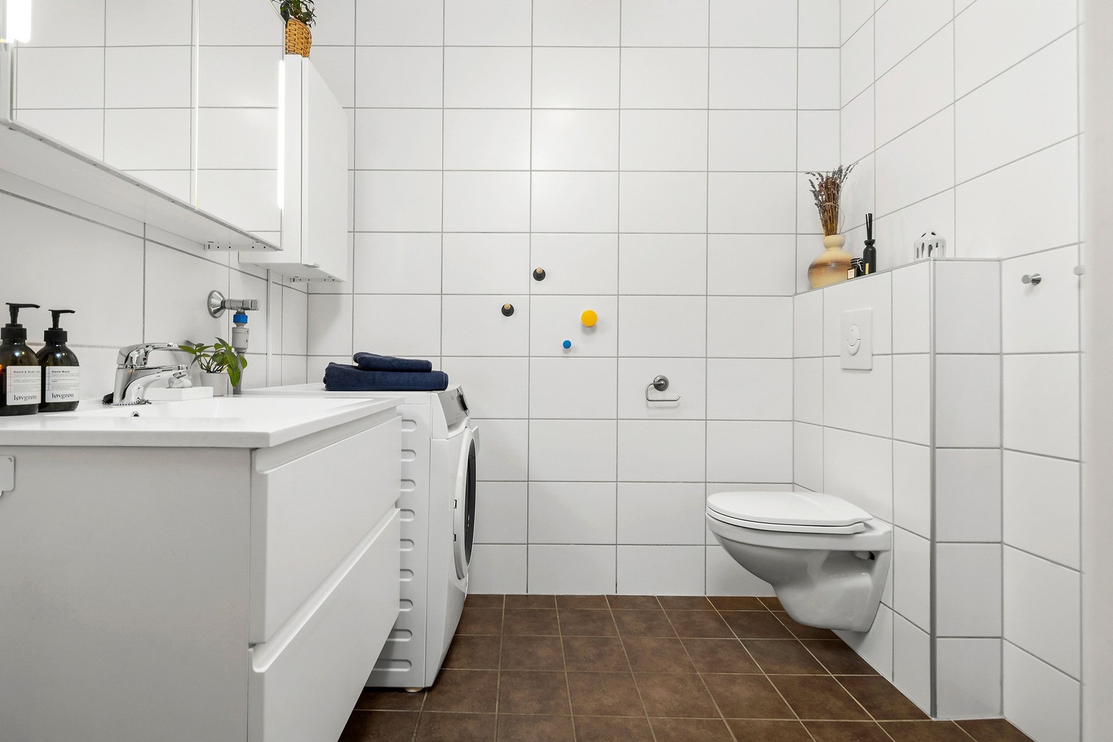 Flott flislagt bad i 1.etasje med servant i skap, vegghengt wc, opplegg for vaskemaskin og dusj. Galleribilde