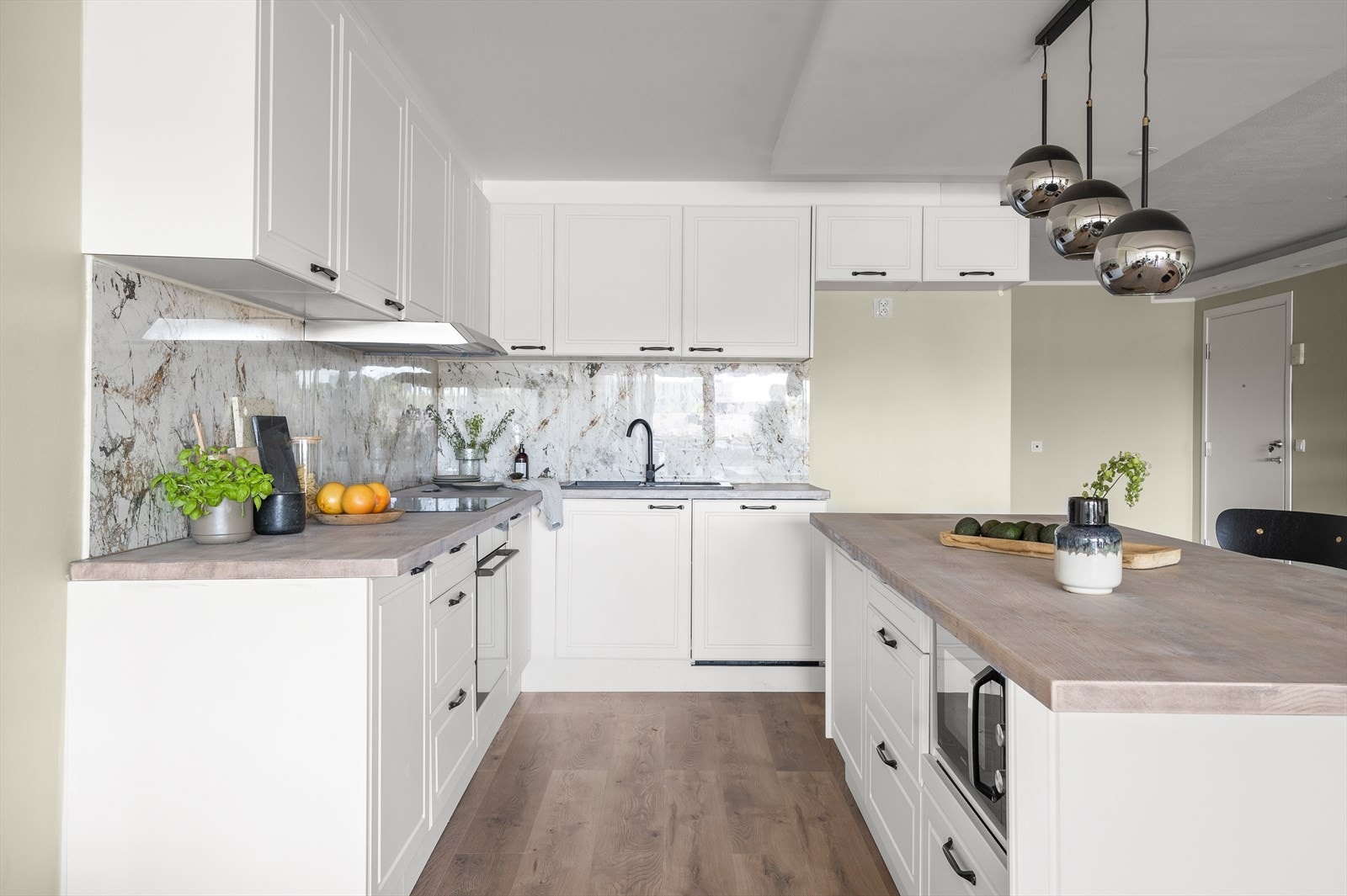 Moderne og velutstyrt kjøkken fra 2023. Integrerte hvitevarer: oppvaskmaskin, komfyr, frittstående mikrobølgeovn. Fliser på vegg over benkeplate Galleribilde